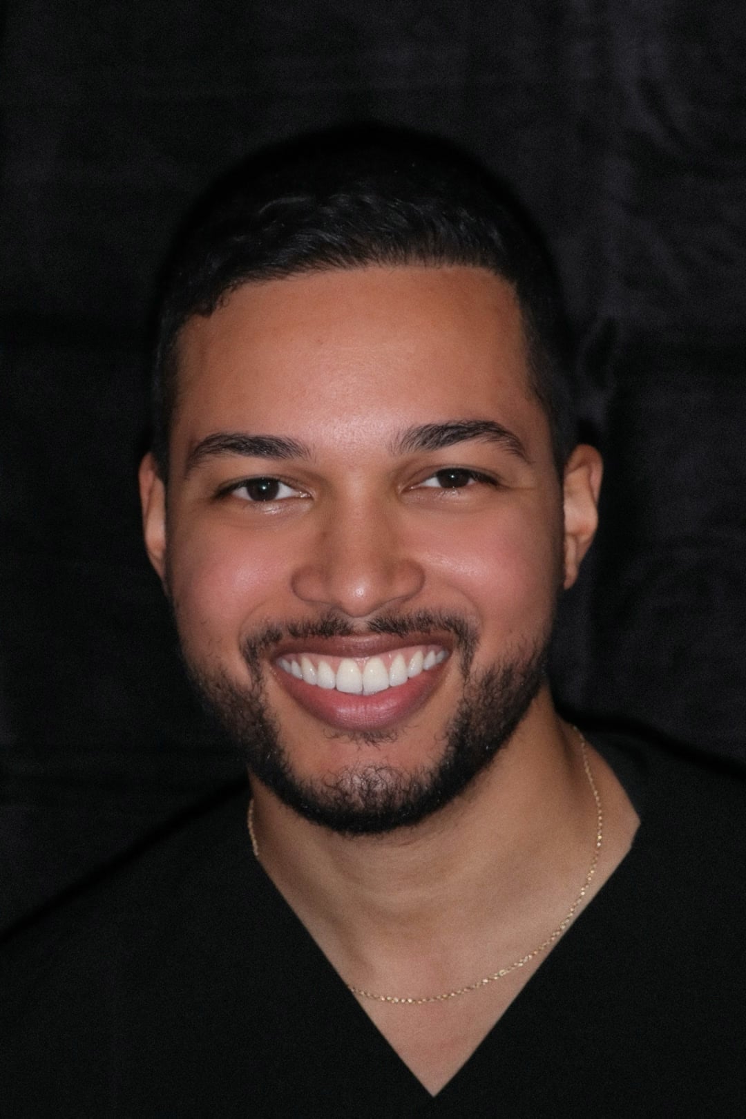 Dr. Hector Cabrera, smiling, in black scrubs